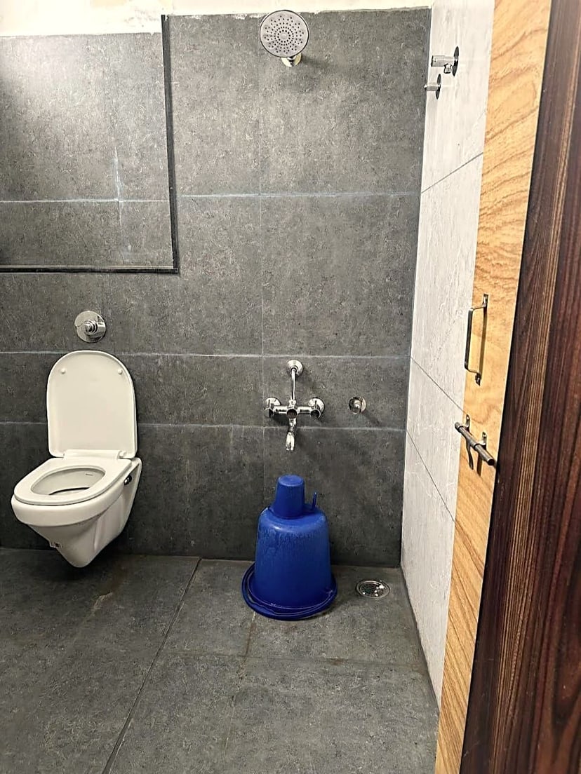 Bathroom with an overhead shower, mirror and grey tiled walls