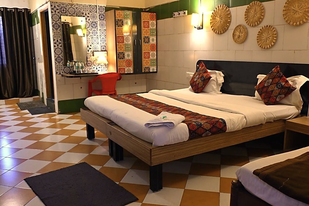 Wide view of a Premium room with twin mattresses made up as a queen and a hand-block print runner
