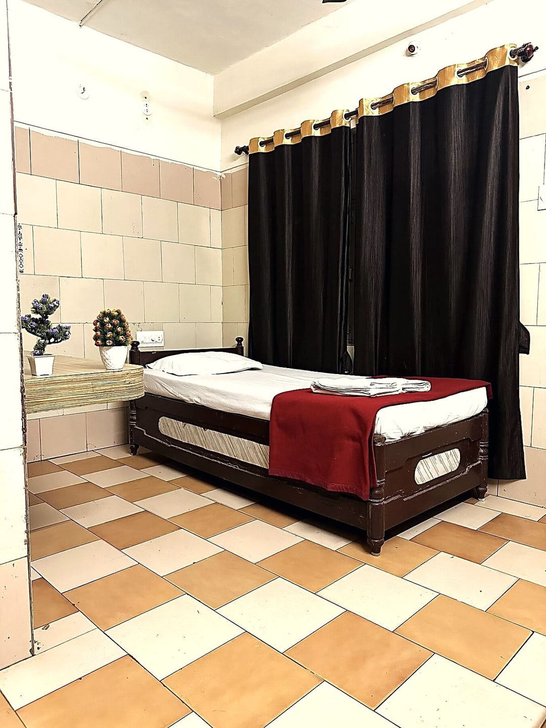 Single room with a full-length curtain, a potted plant and a neatly made single bed