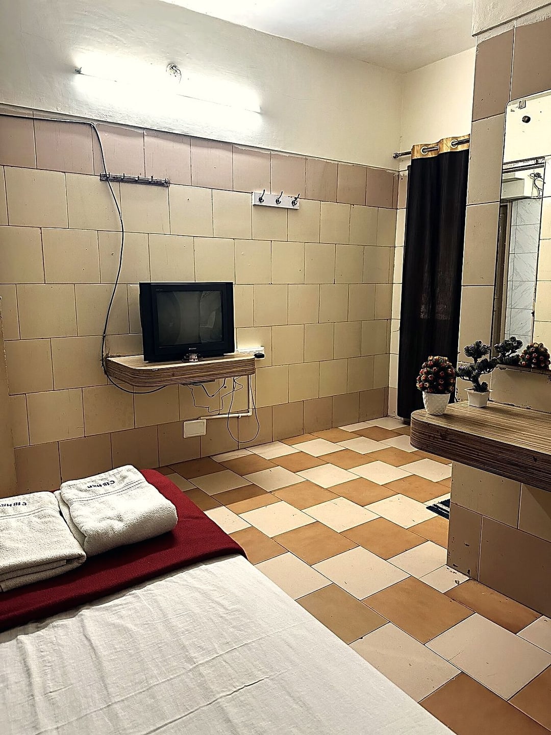 Single room with a wall-mounted television and the en-suite bathroom door